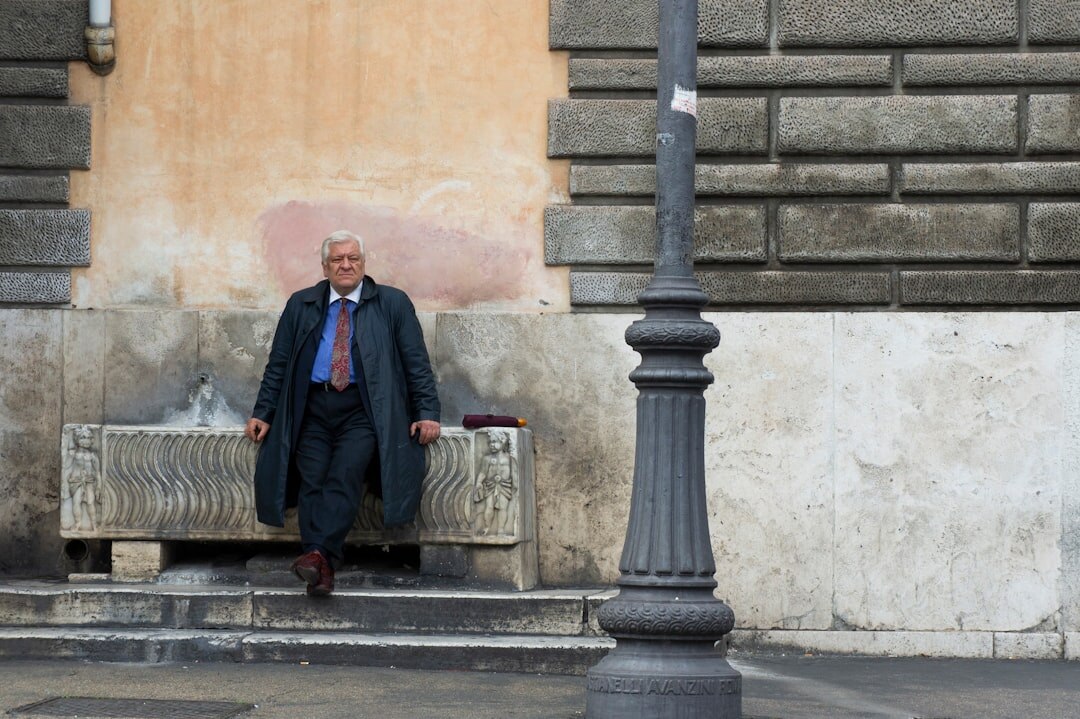 Elderly man reading a newspaper on a stone bench